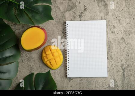 Mango mit Würfeln und leerem Notizbuch auf Marmoroberfläche Stockfoto