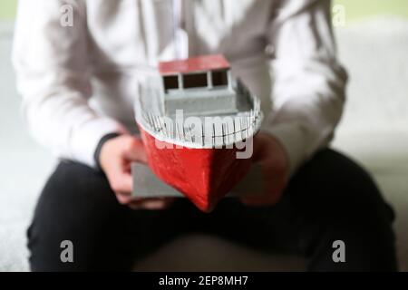 Der Typ hält ein provisorisch behelfsmäßiges Schiff. Eine Yacht, die von einem Jungen gemacht wurde. Ein Spielzeugschiff. Stockfoto