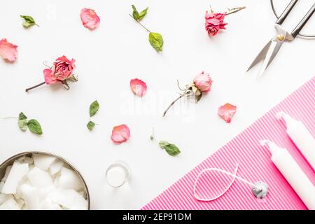 DIY-Konzept. Wachs, Docht, trockene Rosen - Zutaten für die Herstellung von handgefertigten Kerzen auf hellem Hintergrund. Flach liegend. Blick von oben Stockfoto