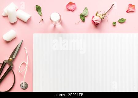 DIY-Konzept. Wachs, Docht, trockene Rosen - Zutaten für die Herstellung von handgefertigten Kerzen auf rosa Hintergrund. Flach liegend. Ansicht von oben mit Kopierplatz Stockfoto