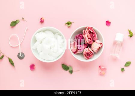 DIY-Konzept. Wachs, Docht, trockene Rosen - Zutaten für die Herstellung von handgefertigten Kerzen auf rosa Hintergrund. Flach liegend. Blick von oben Stockfoto