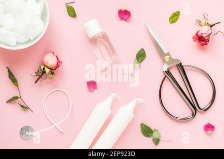 DIY-Konzept. Wachs, Docht, trockene Rosen - Zutaten für die Herstellung von handgefertigten Kerzen auf rosa Hintergrund. Flach liegend. Blick von oben Stockfoto