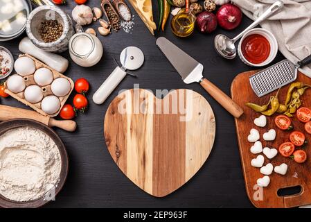 Frau bereitet ein festliches Abendessen für zwei zu Ehren von Valentinstag klassische italienische Pizza Margherita in Form von Ein Herz und Mozzarella im sh Stockfoto