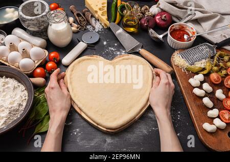 Frau bereitet ein festliches Abendessen für zwei zu Ehren von Valentinstag klassische italienische Pizza Margherita in Form von Ein Herz und Mozzarella im sh Stockfoto