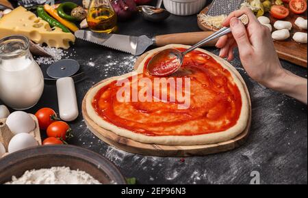 Frau bereitet ein festliches Abendessen für zwei zu Ehren von Valentinstag klassische italienische Pizza Margherita in Form von Ein Herz und Mozzarella im sh Stockfoto