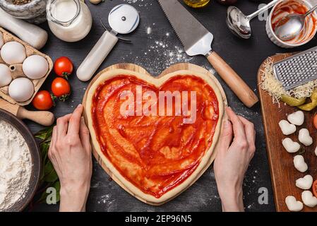 Frau bereitet ein festliches Abendessen für zwei zu Ehren von Valentinstag klassische italienische Pizza Margherita in Form von Ein Herz und Mozzarella im sh Stockfoto