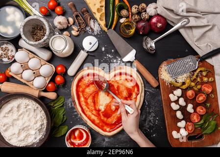 Frau bereitet ein festliches Abendessen für zwei zu Ehren von Valentinstag klassische italienische Pizza Margherita in Form von Ein Herz und Mozzarella im sh Stockfoto