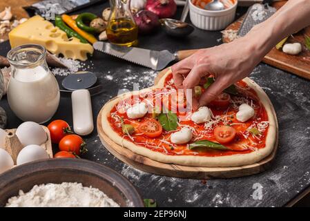 Frau bereitet ein festliches Abendessen für zwei zu Ehren von Valentinstag klassische italienische Pizza Margherita in Form von Ein Herz und Mozzarella im sh Stockfoto