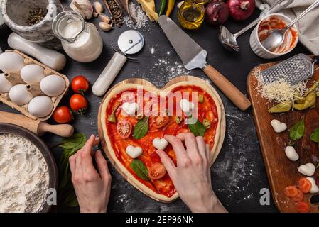Frau bereitet ein festliches Abendessen für zwei zu Ehren von Valentinstag klassische italienische Pizza Margherita in Form von Ein Herz und Mozzarella im sh Stockfoto