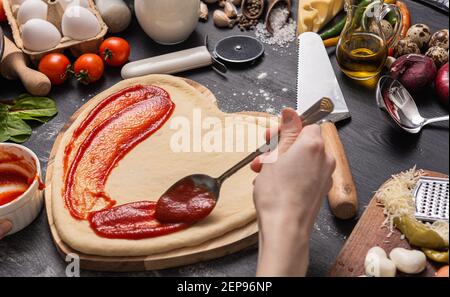 Frau bereitet ein festliches Abendessen für zwei zu Ehren von Valentinstag klassische italienische Pizza Margherita in Form von Ein Herz und Mozzarella im sh Stockfoto
