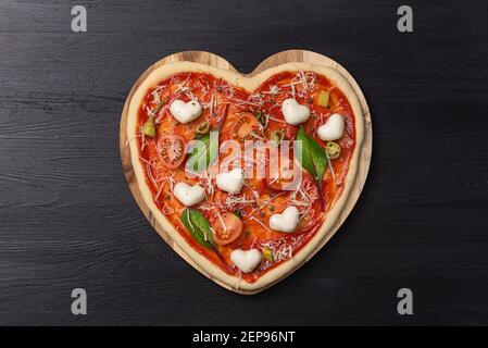 Frau bereitet ein festliches Abendessen für zwei zu Ehren von Valentinstag klassische italienische Pizza Margherita in Form von Ein Herz und Mozzarella im sh Stockfoto