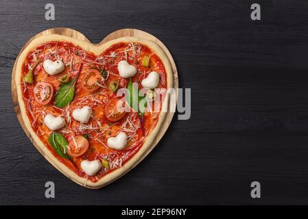Frau bereitet ein festliches Abendessen für zwei zu Ehren von Valentinstag klassische italienische Pizza Margherita in Form von Ein Herz und Mozzarella im sh Stockfoto