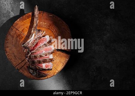 Gegrilltes Cowboy Rindfleisch Steak auf dunklem Hintergrund. Teures marmoriertes Rindfleisch der höchsten Qualität frittiert bis selten auf dem Grill Stockfoto