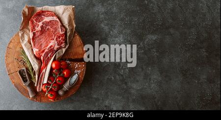 Frisches rohes Cowboy Tomahawk Steak auf einem runden Holzschnitt Brett für Fleisch Stockfoto