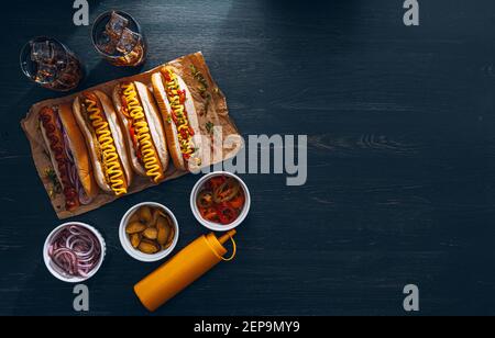 Amerikanischer Hot Dog mit Zutaten auf dunklem Holzhintergrund Stockfoto