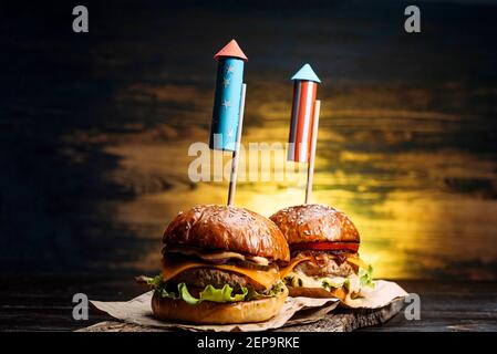 Nahaufnahme Bild von zwei Rindfleisch Burger mit Feuerwerk Raketen. Picknick festlichen Snack am 4. juli Unabhängigkeitstag Stockfoto