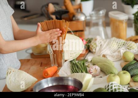 Die Hände des Kindes schließen sich, während er die Spaghetti im Glas gerade macht. Stockfoto