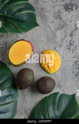 Geschnittene Mango und reife Avocado-Früchte auf Marmoroberfläche Stockfoto