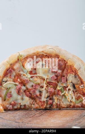 Vertikales Foto der Hälfte der gemischten Pizza auf Holzhintergrund Stockfoto