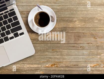 Großer Blick auf den Schreibtisch mit Kopierfläche. Tisch mit Laptop und Tasse Kaffee. Flach liegend. Freiberuflicher oder studentischer Schreibtisch. Draufsicht mit Kopierbereich fo Stockfoto