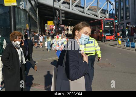 Eine Frau, die eine Gesichtsmaske als Schutz gegen das Coronavirus (covid-19) trägt, geht an einer Straße in London Bridge, London, Großbritannien vorbei Stockfoto