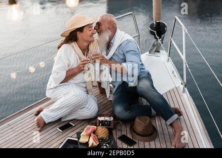 Ältere Paare jubeln mit Champagner auf Segelboot während der Sommerferien - Fokus auf das Gesicht des Menschen Stockfoto