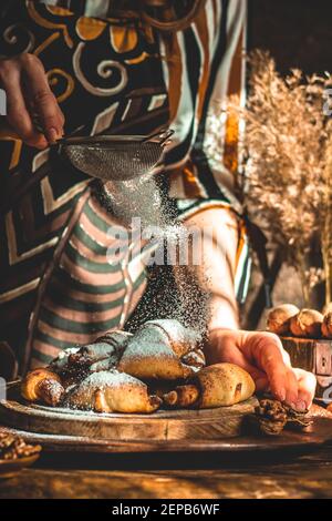 Frau streut mit hausgemachten Puderbrötchen. Stockfoto