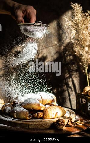 Frau streut mit hausgemachten Puderbrötchen. Stockfoto