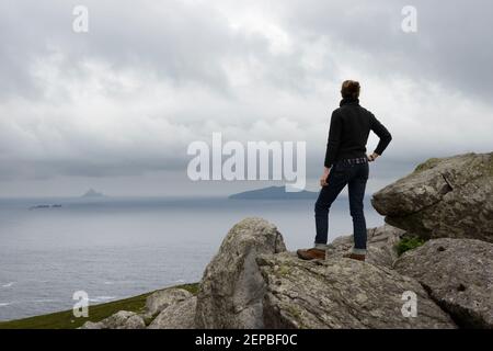 Eine Wanderin, die den Blick auf die Great Blasket Island von Clogher Head auf der irischen Halbinsel Dingle bewundert. Stockfoto