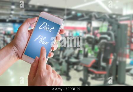 Hand halten Smartphone mit Diät-Plan gesunde Ernährung, Diät, Schlankheits-und Gewichtsverlust Konzept mit Blur Fitness-Shop Hintergrund Stockfoto