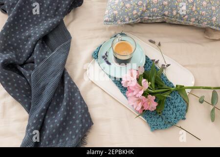 Angenehme romantische Frühstücksszene auf dem Bett am Morgen mit Kaffee und Blumen. Stockfoto