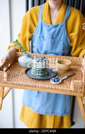 Frau hält Rattan Tablett mit blauen amerikanischen Pfannkuchen Stockfoto