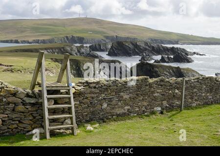 Ein hölzerner Stil, der eine Trockensteinmauer auf der Insel von St. Ninian's, Shetland, umspannt. Stockfoto