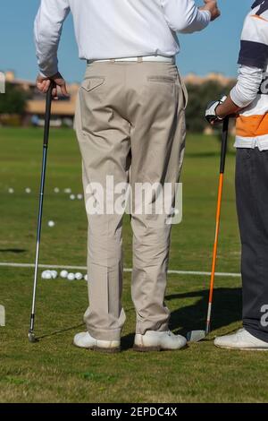 Rahmen von zwei Golfern, mit dem Rücken gedreht, diskutieren Golf, während sie ihre Schläger und viele Bälle auf dem Feld. Stockfoto