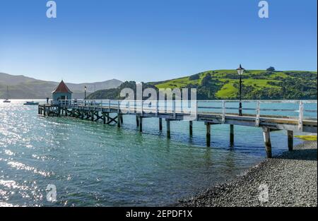 Idyllische Landschaft mit Holzsteg rund um Akaroa, eine kleine Stadt in der Canterbury Region der Südinsel Neuseelands Stockfoto