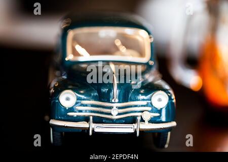 Makroaufnahme eines englischen blauen Spielzeugautos mit minimalem Fokus. Eine Kerze auf der rechten Seite erzeugt eine Lichtreflexion im Auto. Stockfoto