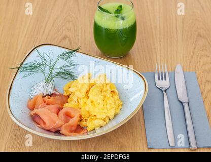 Serviert Frühstück mit geräuchertem Lachs, Rührei, ein wenig Frischkäse und eine Entgiftung grünen Saft zu trinken. Stockfoto