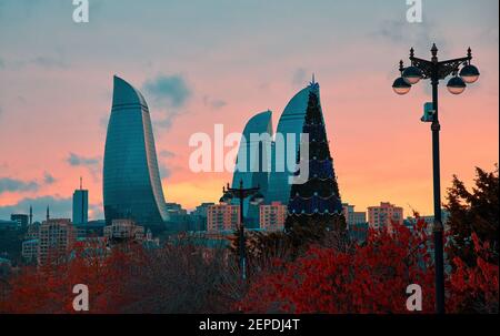 Baku, Aserbaidschan - 22. Dezember 2017: Skyline von Baku, Flammentürme und Weihnachtsbaum bei Sonnenuntergang am Dezemberabend kurz vor Weihnachten. Stockfoto