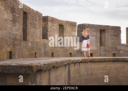 Eine junge blonde Touristin erkundet die Stadtmauern der befestigten mittelalterlichen Zitadelle der Altstadt von Carcassonne, Frankreich. Stockfoto