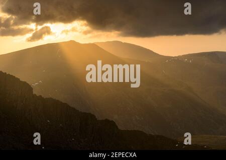 Crepuscular Strahlen beleuchten die Landschaft rund um Y Garn in der Glyderauer Berge, Snowdonia. Stockfoto