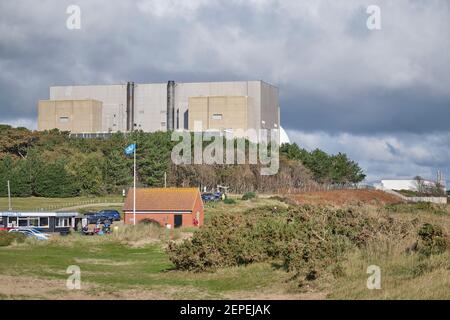 Sizewell EIN Reaktorgebäude, das über einem öffentlichen Toilettenblock, einem Café und einem Fahnenmast am Sizewell-Strand in Suffolk thront. Suffolk-Flagge fliegt über dem öffentlichen Gebäude Stockfoto