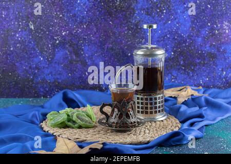 Teekanne und ein Glas Tee mit trockenem Kiwi Blauer Hintergrund Stockfoto