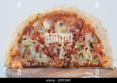 Die Hälfte der gemischten Pizza auf Holzbrett auf weißem Hintergrund Stockfoto