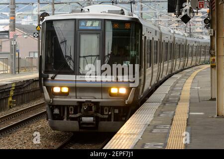 Ein JR-Regionalzug, der zu einem Bahnhof auf der Kyoto-Osaka-Linie in Japan fährt. Stockfoto