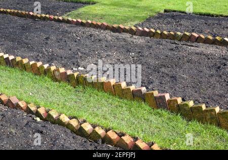 Vorbereiten eines neuen leeren Blumenbeet mit Sägezahn Ziegel Einfassung in Ein britischer Garten Stockfoto