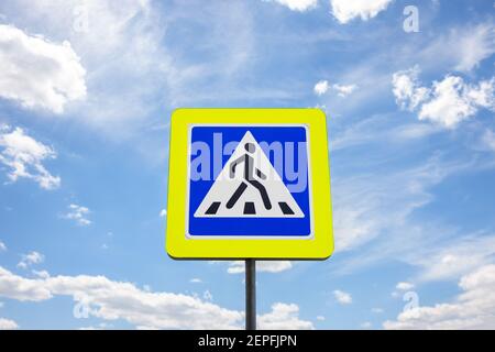 Blaue Fußgängerübergangsschild mit schönen weißen Wolken am blauen Himmel. Sonniger Tag. Crosswalk-Konzept Stockfoto