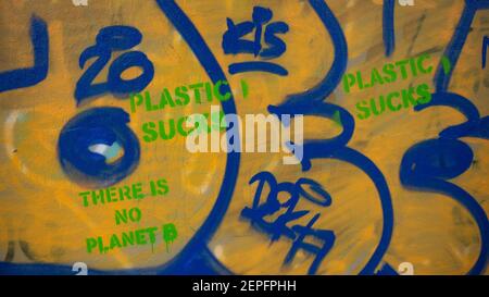 Wandgraffiti mit 'Plastic Sucks' und 'There is No Planet B' Slogan in grün auf gelbem Hintergrund Graffiti. Stockfoto