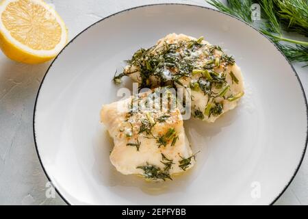 Kabeljau mit Dill gebacken und auf einem Teller serviert. Stockfoto