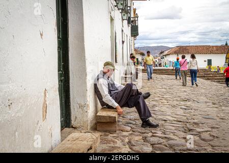 Kolumbianischer Mann verwittert Gesicht, sitzen außerhalb Bar.Villa de Leyva Hauptplatz 500 Jahre alte Stadt. Bergkette. Boyaca, Kolumbien, Anden, Südamerika Stockfoto