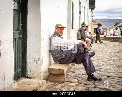 Kolumbianischer Mann verwittert Gesicht, sitzen außerhalb Bar.Villa de Leyva Hauptplatz 500 Jahre alte Stadt. Bergkette. Boyaca, Kolumbien, Anden, Südamerika Stockfoto